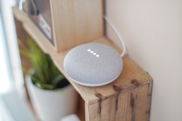 A Google home assistant sitting on a bookcase